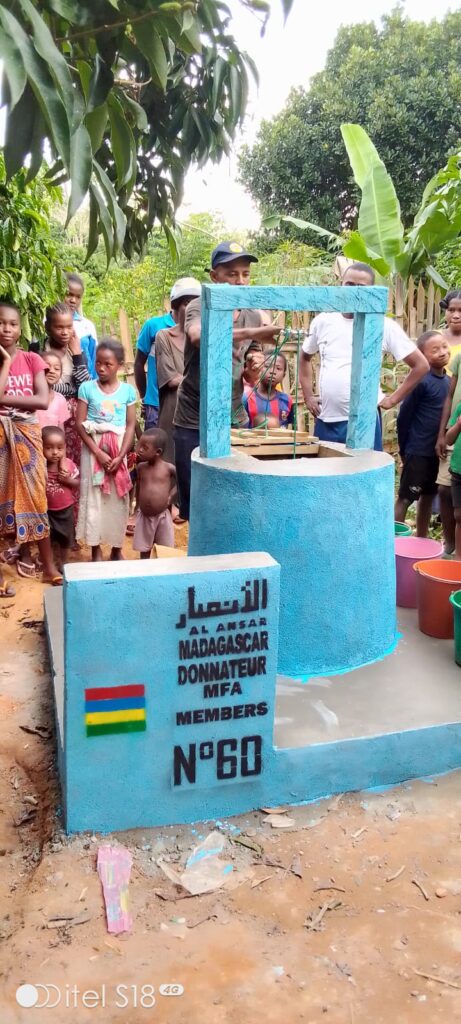 A newly built water well with community members gathered around it in Madagascar